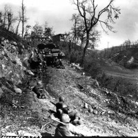 Genieri della 10° Divisione di Montagna riposano mell'ultima fila di un distruttore di carri che offre loro un po' di protezione dal fuoco dei franchi tiratori sulla strada durante l'assalto della 10° Divisione da Montagna della 5° Armata.